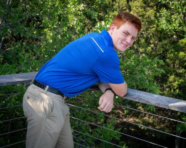 Handsome, red- headed young man posing for his High School graduation photos. Very attractive and athletic looking young boy.