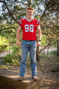 Handsome, red- headed young man posing for his High School graduation photos. Very attractive and athletic looking young boy.