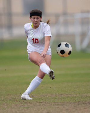Genç çekici atletik kız bir oyunda futbol oynuyor.