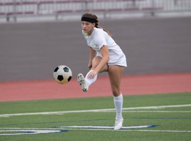 Genç çekici atletik kız bir oyunda futbol oynuyor.