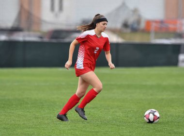 Genç çekici atletik kız bir oyunda futbol oynuyor.