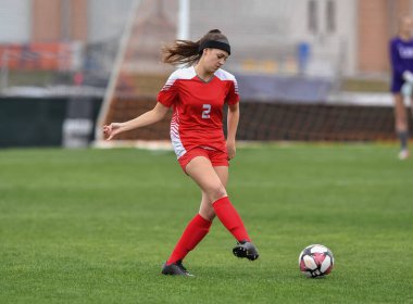 Genç çekici atletik kız bir oyunda futbol oynuyor.