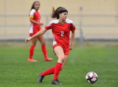 Genç çekici atletik kız bir oyunda futbol oynuyor.