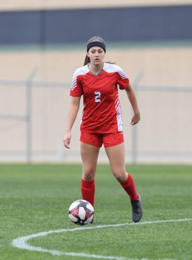 Genç çekici atletik kız bir oyunda futbol oynuyor.