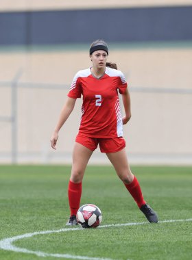 Genç çekici atletik kız bir oyunda futbol oynuyor.