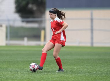 Genç çekici atletik kız bir oyunda futbol oynuyor.