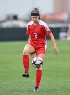 Genç çekici atletik kız bir oyunda futbol oynuyor.