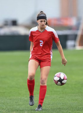 Genç çekici atletik kız bir oyunda futbol oynuyor.