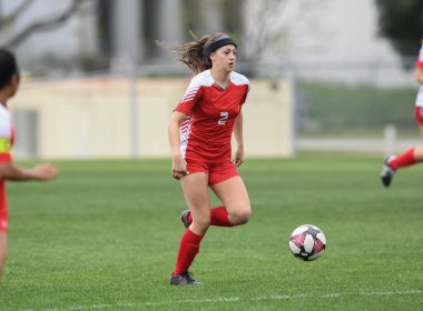 Genç çekici atletik kız bir oyunda futbol oynuyor.