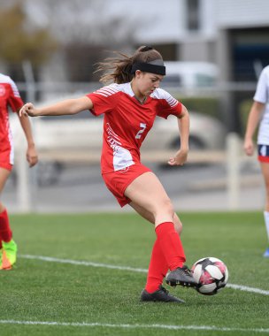 Genç çekici atletik kız bir oyunda futbol oynuyor.