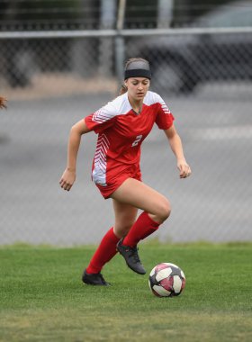 Genç çekici atletik kız bir oyunda futbol oynuyor.