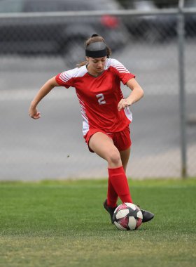 Genç çekici atletik kız bir oyunda futbol oynuyor.