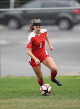 Genç çekici atletik kız bir oyunda futbol oynuyor.