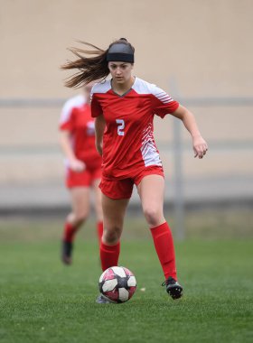 Genç çekici atletik kız bir oyunda futbol oynuyor.