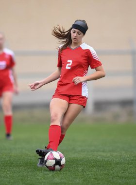 Genç çekici atletik kız bir oyunda futbol oynuyor.