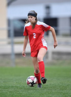 Genç çekici atletik kız bir oyunda futbol oynuyor.