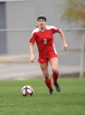 Genç çekici atletik kız bir oyunda futbol oynuyor.