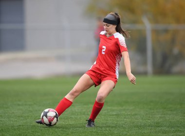 Genç çekici atletik kız bir oyunda futbol oynuyor.