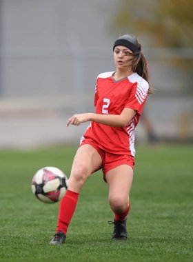 Genç çekici atletik kız bir oyunda futbol oynuyor.