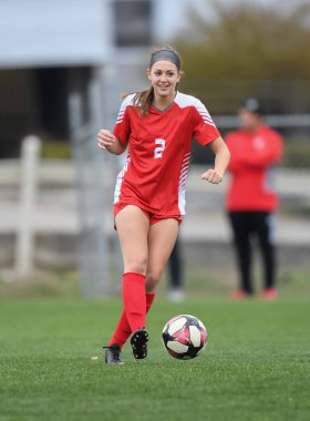 Genç çekici atletik kız bir oyunda futbol oynuyor.