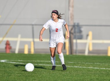 Genç çekici atletik kız bir oyunda futbol oynuyor.
