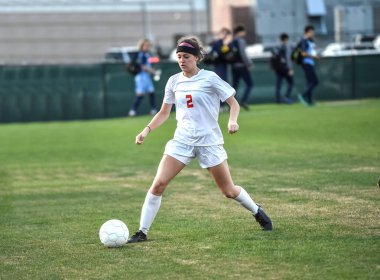 Genç çekici atletik kız bir oyunda futbol oynuyor.