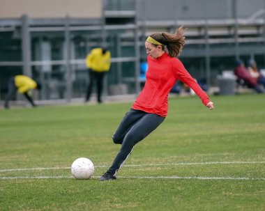 Genç çekici atletik kız bir oyunda futbol oynuyor.