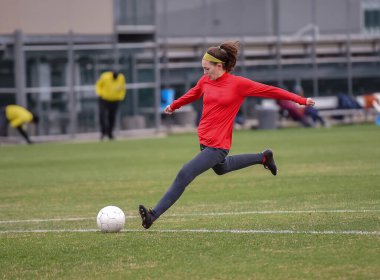 Genç çekici atletik kız bir oyunda futbol oynuyor.
