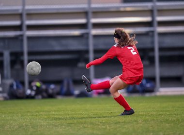 Genç çekici atletik kız bir oyunda futbol oynuyor.