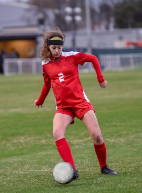 Genç çekici atletik kız bir oyunda futbol oynuyor.