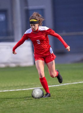 Genç çekici atletik kız bir oyunda futbol oynuyor.