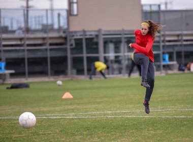 Genç çekici atletik kız bir oyunda futbol oynuyor.