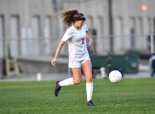 Young attractive athletic girl playing soccer in a game
