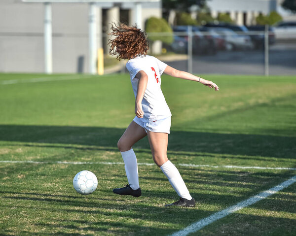 Young attractive athletic girl playing soccer in a game