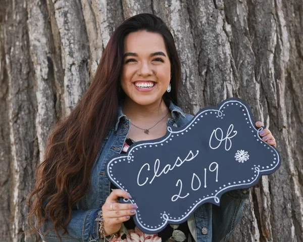 Young Female High School Senior posing for Senior photos in a beautiful park setting