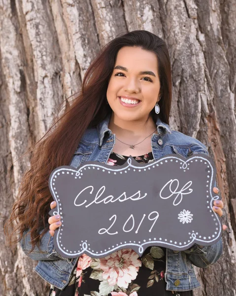 Young Female High School Senior posing for Senior photos in a beautiful park setting