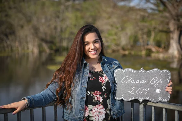 Young Female High School Senior posing for Senior photos in a beautiful park setting