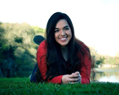 Genç bayan lise son sınıf öğrencisi güzel bir park ortamında son sınıf fotoğraflarına poz veriyor.