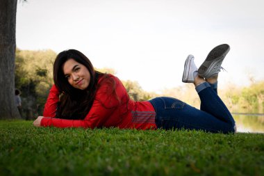 Genç bayan lise son sınıf öğrencisi güzel bir park ortamında son sınıf fotoğraflarına poz veriyor.