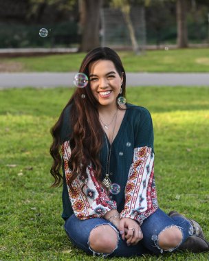 Genç bayan lise son sınıf öğrencisi güzel bir park ortamında son sınıf fotoğraflarına poz veriyor.