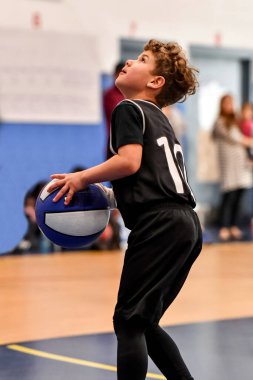 Genç sporcu çocuk maç sırasında harika basketbol oynuyor.