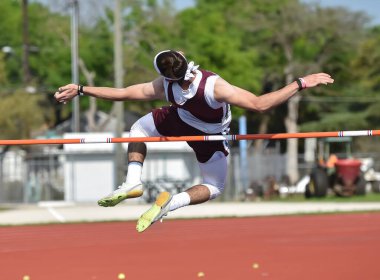 Erkek sporcular bir atletizm yarışmasında yüksek atlama yapıyorlar.