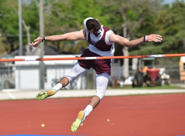 Erkek sporcular bir atletizm yarışmasında yüksek atlama yapıyorlar.