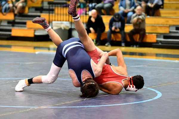 Athletic male wrestlers competing at a wrestling meet.