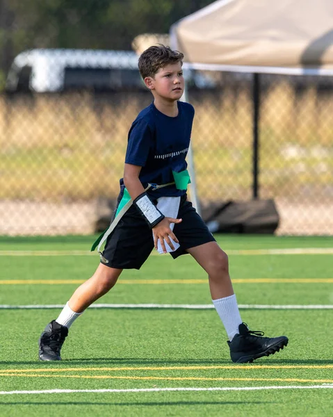 Genç atletik çocuk bayrak futbolunda oynuyor.