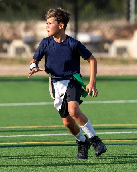 Genç atletik çocuk bayrak futbolunda oynuyor.