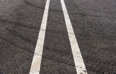 Yeni bir asfalt yolda araba lastiği izleri.