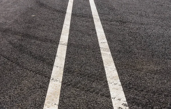 Yeni bir asfalt yolda araba lastiği izleri.