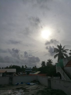 Gün batımında yağmur bulutları etrafını sarar. Bulutlar koyu renklidir ve hindistan cevizi ağaçları gölgesini gökyüzünde oluşturur. Bulutlar yeterince uzundur..