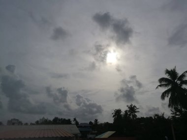 Gün batımında yağmur bulutları etrafını sarar. Bulutlar koyu renklidir ve hindistan cevizi ağaçları gölgesini gökyüzünde oluşturur. Bulutlar yeterince uzundur..